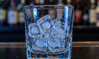 Eisw&uuml;rfel in Kristallglas mit Kondenswasser und blauer Neon-Reflexion f&uuml;r Casea Daily Cashback