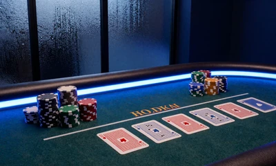 Live Casino Hold'em Poker-Tisch mit Community Cards und Chips in blau beleuchtetem Studio